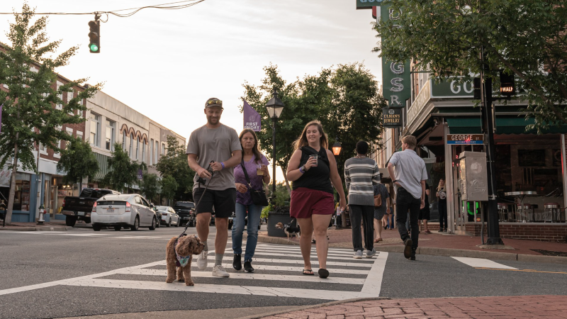 Family and dog walking across crosswalk in downtown Fredericksburg